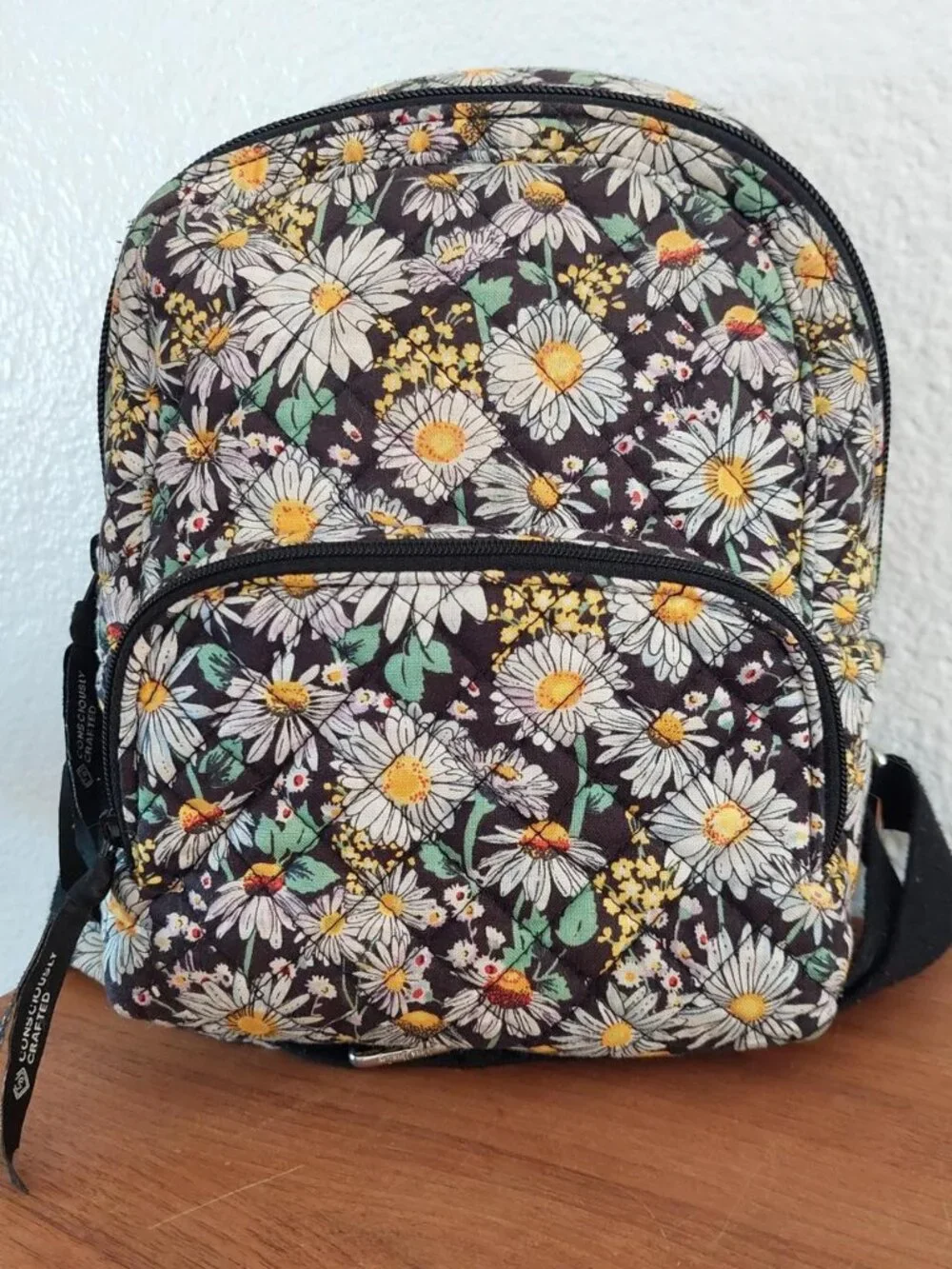 Vera Bradley Daisy Floral Backpack with white daisies and yellow centers on a da